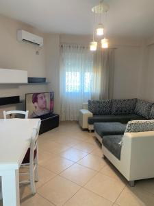 ein Wohnzimmer mit einem Sofa und einem TV in der Unterkunft Apartament Orestiada in Vlorë