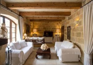 a living room with white couches and a stone wall at Betty Cake B&B in Qala