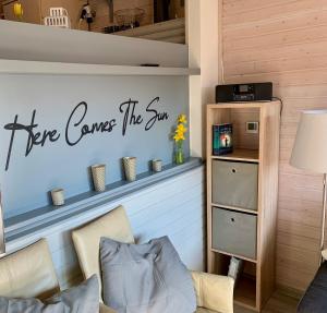 a living room with a sign that says here comes the sun at Idylle Seepark - Haus mit Pool und Fasssauna in Kirchheim