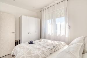 a white bedroom with a bed and a large window at Apartment La Perla in Đenovići