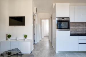 a kitchen with white cabinets and a tv on the wall at Apartment La Perla in Đenovići