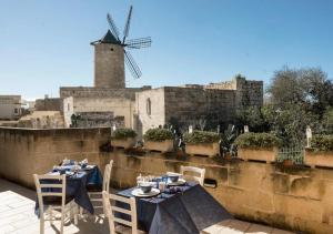 a table and chairs on a roof with a windmill at Betty Cake B&B in Qala