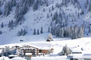 eine Skihütte im Schnee mit einem Berg in der Unterkunft Hotel Berghof in Lech am Arlberg