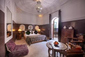 een slaapkamer met een bed, een tafel en een stoel bij Riad Bohémia in Marrakesh