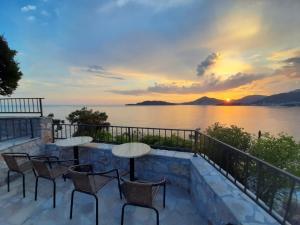 a patio with tables and chairs overlooking the water at sunset at Apartments Mitrovići Miločer in Sveti Stefan