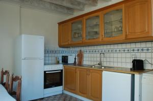 eine Küche mit Holzschränken und einem weißen Kühlschrank in der Unterkunft Rêv'Arles Maison de charmes aux Arènes in Arles