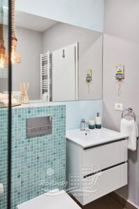 La salle de bains est pourvue d'un lavabo blanc et de carrelage bleu. dans l'établissement RoApart Mamaia - Sea View Maia, à Mamaia Nord – Năvodari