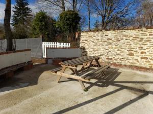 een houten picknicktafel naast een stenen muur bij location petit gite individuel in Orgères