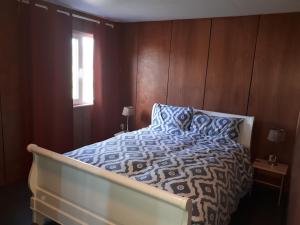 Hensbroek的住宿－A-frame volledig vrijstaande woning，一间卧室配有一张带蓝色和白色棉被的床和窗户。