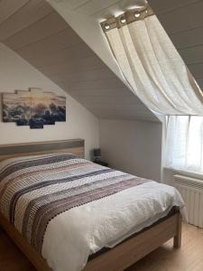 um quarto com uma cama e uma janela em Au passe temps em Beaucourt