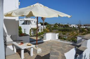 a patio with an umbrella and a table at Paros Traditional Country House in Parikia