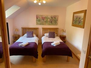 2 aparte bedden in een kamer met paarse lakens bij Tulach Ard in Grantown on Spey
