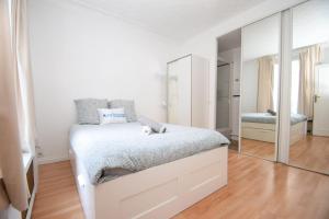 ein weißes Schlafzimmer mit einem Bett und einem Spiegel in der Unterkunft Top location near ParisSuperb cosy 2p apartment in Vincennes