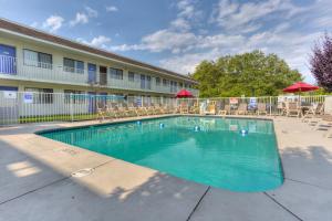 a swimming pool in front of a hotel with tables and chairs at Motel 6-Troutdale, OR - Portland East in Troutdale