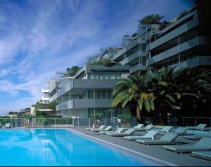 - une piscine avec des chaises longues devant un bâtiment dans l'établissement Costa Plana apartment 528 (3km from Monaco), à Cap d'Ail