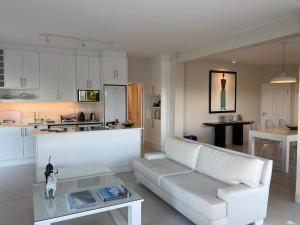 a living room with a white couch and a table at Stella Maris Luxury Apartment in Plettenberg Bay