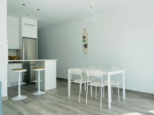 biała kuchnia ze stołem i krzesłami w obiekcie Precioso apartamento con vistas parciales, garaje y piscina w mieście Tarifa