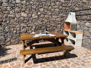 uma mesa de madeira e um banco em frente a uma parede de pedra em Casa Guergue by VV Canary Ocean Homes em Masca