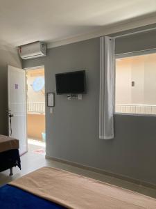 1 dormitorio con TV de pantalla plana en la pared en Pousada A Casa Portuguesa, en Cabo de Santo Agostinho