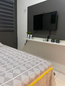 a bedroom with a bed with a tv on a wall at Flat JK 102 in Juazeiro do Norte