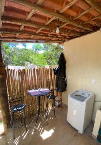 a patio with a table and chairs and a washing machine at Casa Estúdio com cozinha completa - Centro Serra do Cipó in Serra do Cipo