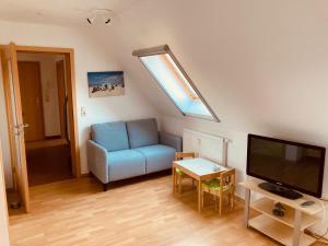 ein Wohnzimmer mit einem blauen Sofa und einem TV in der Unterkunft Ferienwohnungen am Badesteig - dem Strand so nah in Dierhagen