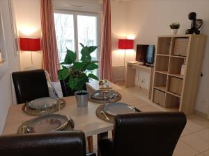 a dining room with a table and chairs and a television at Résidence de la Source by Euclenima in Salies-de-Béarn