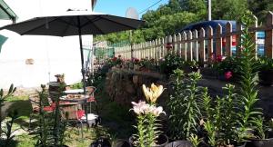 a garden with a table and an umbrella and flowers at Kuća Talija in Kalna