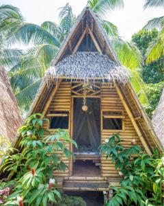 a small bamboo house with a thatched roof at Mango Tree Eco-Hostel in Dauin