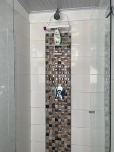 y baño con ducha y pared de azulejos. en Habitación privada en casa de familia cerca del CC VIVA Envigado en Itagüí