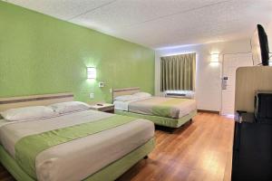 two beds in a room with green walls at Motel 6 Austin, TX - Central Downtown UT in Austin