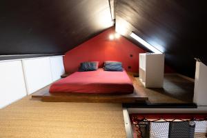 a bedroom with a red bed in the attic at Capsule Cinéma - Balneo home cinema playstation 5 in Valenciennes