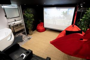 a bathroom with a red umbrella and a video screen at Capsule Cinéma - Balneo home cinema playstation 5 in Valenciennes