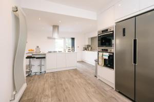 a kitchen with white cabinets and stainless steel appliances at The White House - Grand & Spectacular 5-bed, sleeps 14- Central Solihull, NEC, JLR, HS2, Resorts World, Airport in Solihull