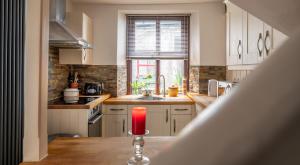 una vela roja sentada en una mesa en una cocina en Kasbah cosy cottage Kendal en Kendal
