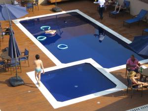 a man standing next to a blue swimming pool at Hotel Estilo de Minas in Diamantina