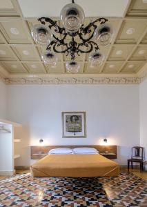 a bedroom with a bed and a ceiling with a chandelier at DOMUS ALERIA Deluxe Rooms in Sciacca