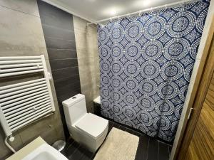 a bathroom with a toilet and a blue and white shower curtain at Panoramic Sea View 2 Bedroom Apartment in Jbeil