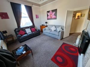 uma sala de estar com um sofá e uma televisão em Parterre Holiday Apartments em Sandown