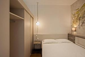Dormitorio pequeño con cama blanca y lámpara en Appartement E RONDINELLE 2, en Belgodère