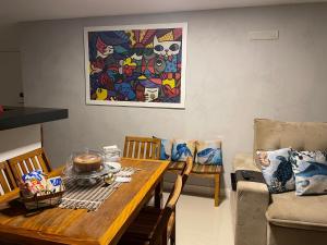 a dining room with a table and a painting at Condomínio novíssimo com total estrutura para vc in Arraial do Cabo