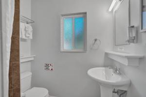 uma casa de banho branca com um lavatório, um WC e uma janela. em The Worthington Resorts - Clothing Optional - Men Only - Solo hombres em Fort Lauderdale
