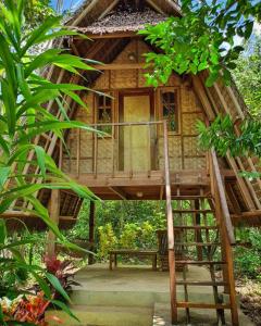 a tree house with a deck and a bench at Lazy Lizard Hostel in Siquijor