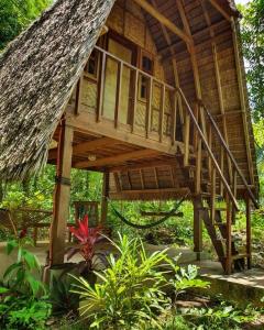 a tree house with a staircase in a garden at Lazy Lizard Hostel in Siquijor