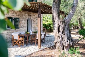 ein Steinhaus mit einem Tisch und Stühlen unter einer Pergola in der Unterkunft Villa Eleni in Gaios