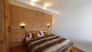 a bedroom with a bed with a wooden wall at Bungalow mit Terrasse im alpinen Stil in Schliersee