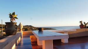 una mesa y bancos en un balcón con vistas al océano en Pantelleria Dammusi Belvedere, en Pantelleria