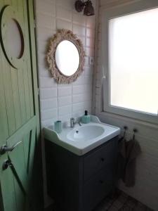 a bathroom with a sink and a mirror and a window at Erdőalján Házikó in Sukoró