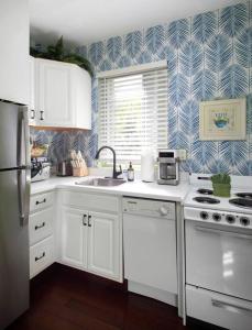 a kitchen with white cabinets and a blue and white wallpaper at Duval Street Suite with pool in Key West