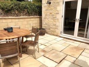 a patio with a wooden table and chairs at Folly Cottage & The Old Forge in Colerne
